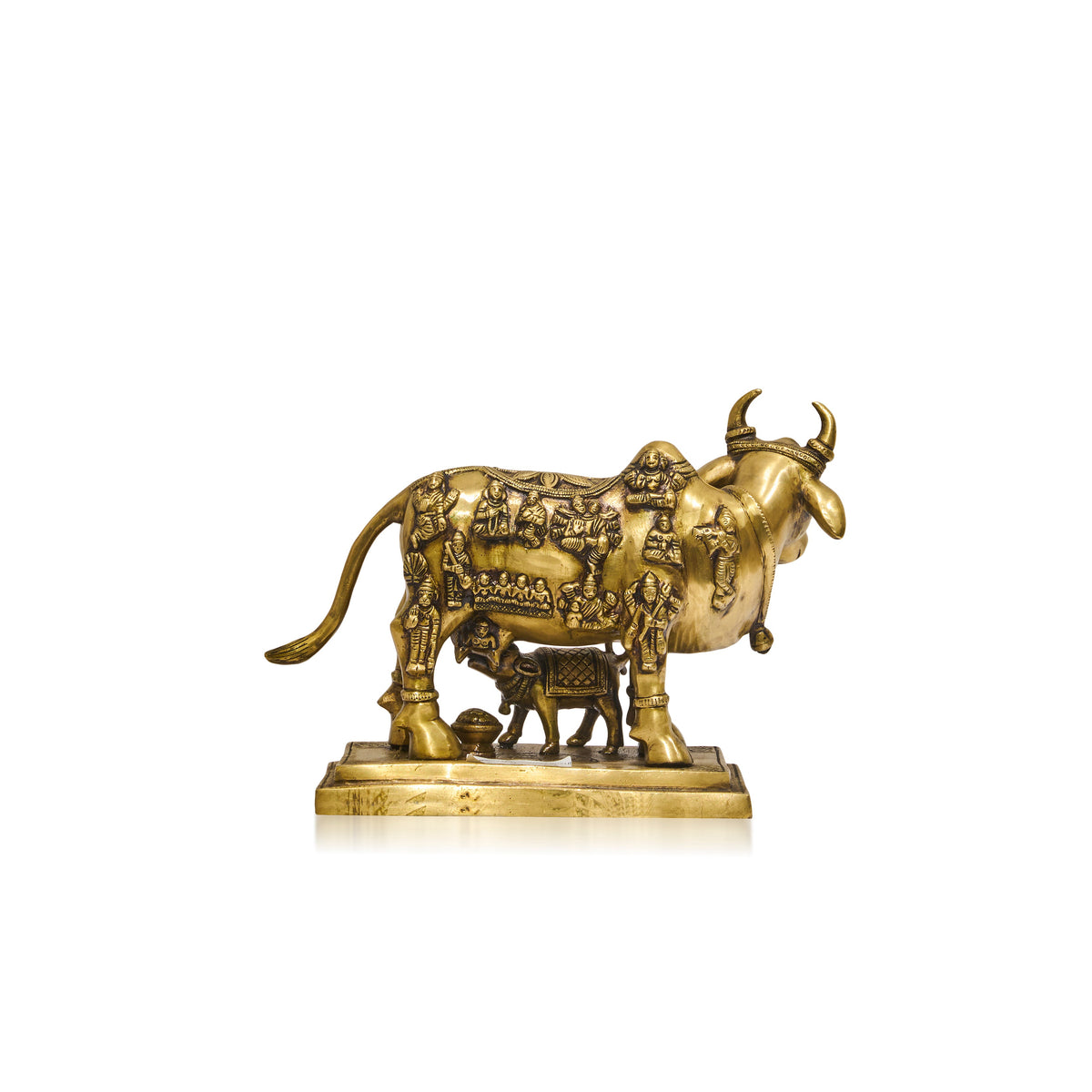 A small brass-colored decorative sculpture of a cow standing on a rectangular base,